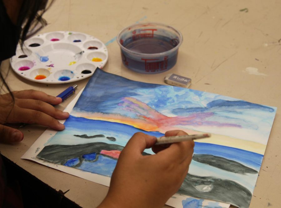 A Drawing and Painting student works on a beach landscape.